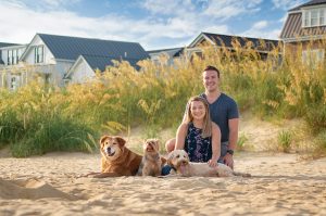 Dogs and their people pose on on a sandy dune