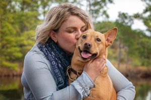 Keeping pets safe outdoors, a woman hugs and kisses her dog