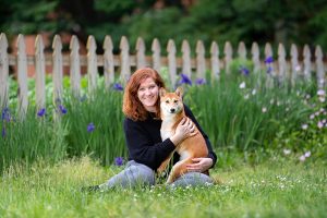 A woman posing with her Shiba Inu dog among the flowers in Norfolk VA