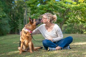A woman gets a kiss from her German Shepherd dog.
